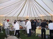 People putting food on their plates in a marquee at a hog roast event